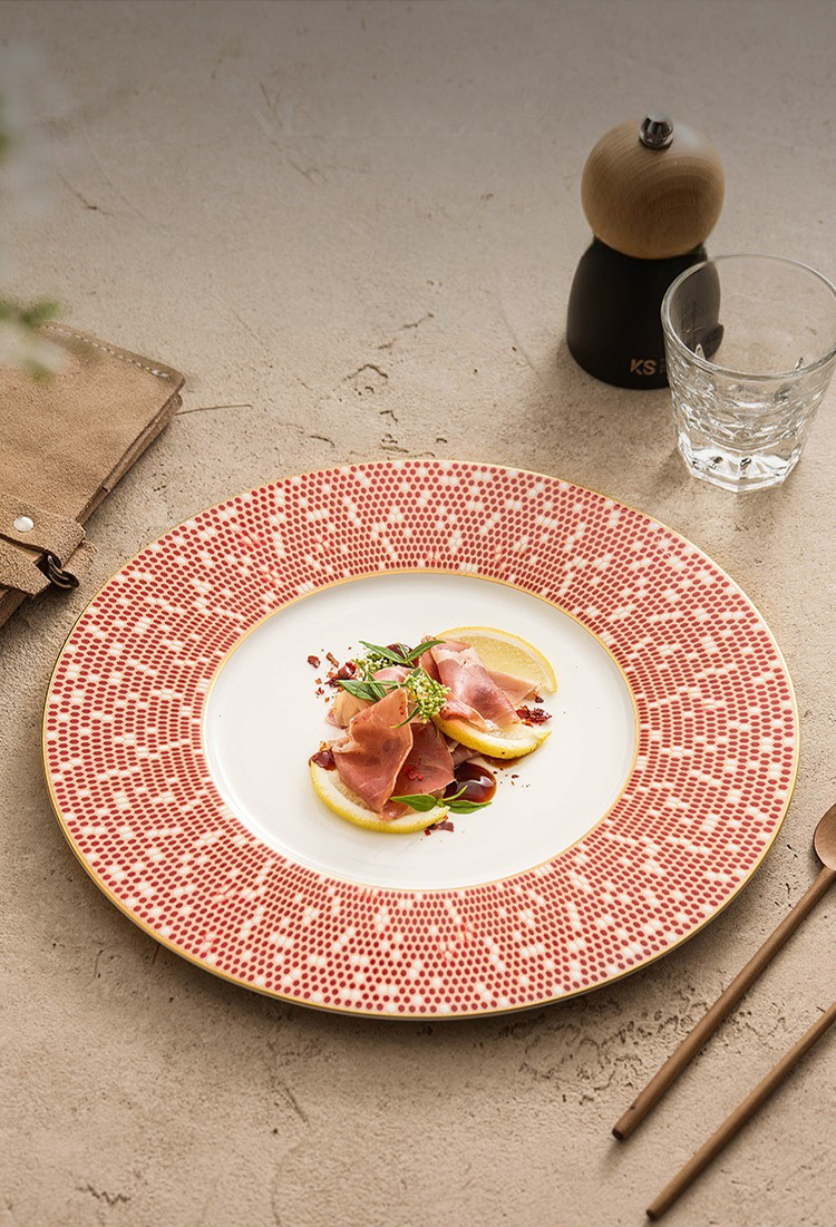 Side view of a slim Celestial Series plate showing the golden-hued base and red rim.