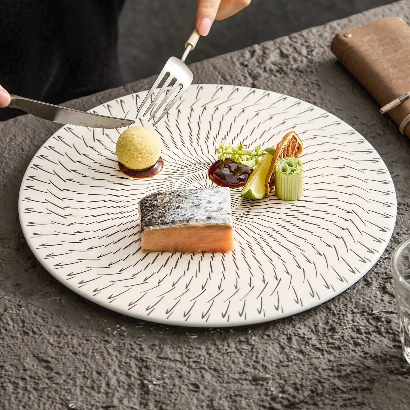 Delicate dish with salmon and vegetables on a decorative plate, set on a textured surface.