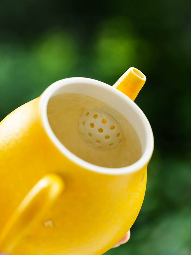 Teapot lid detail featuring a hand-painted yellow camellia against a white porcelain background.