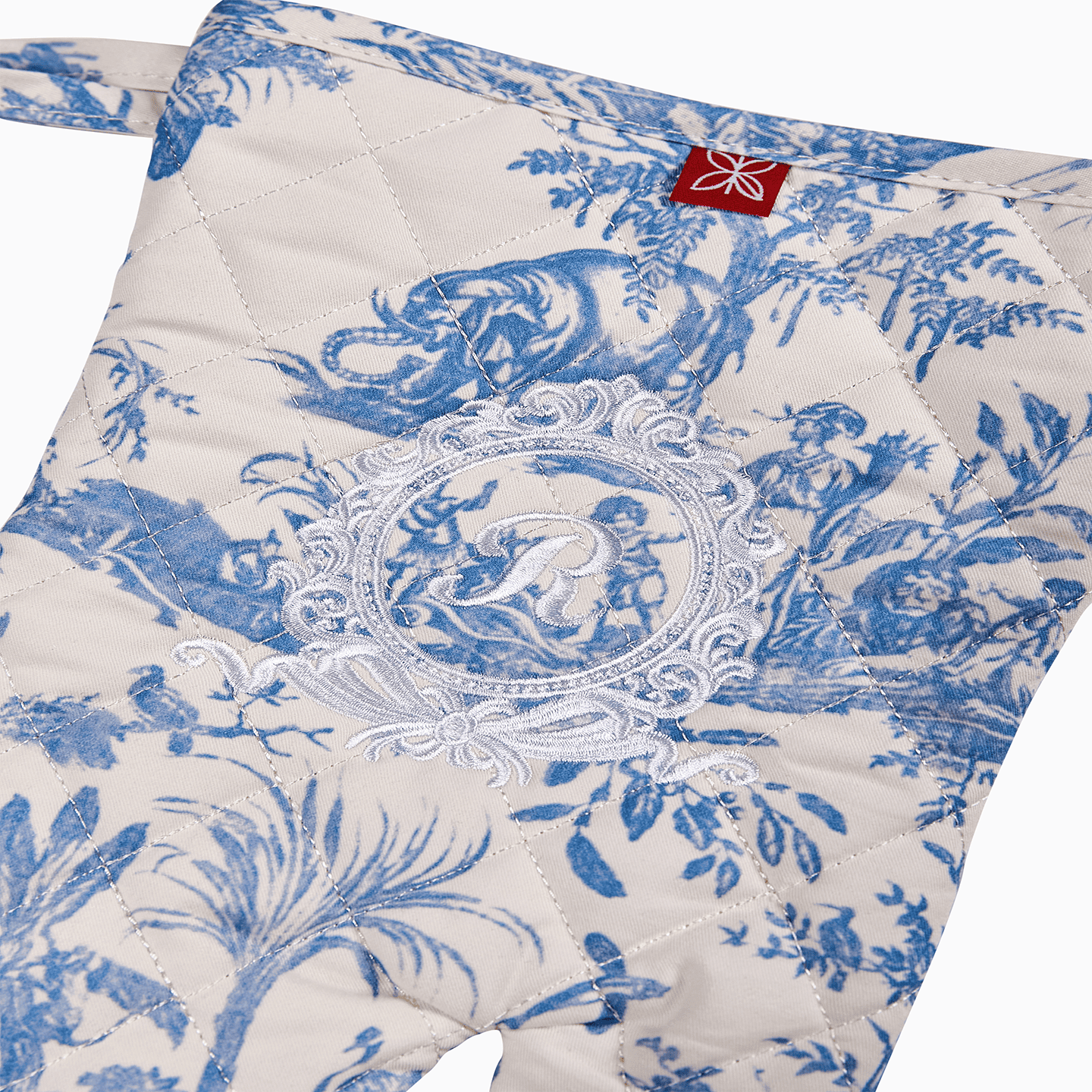 The hanging loop detail on a blue 100% cotton Toile de Jouy oven mitt.