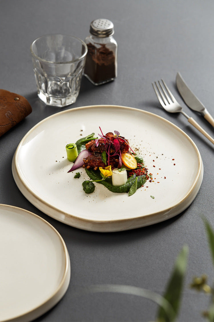 Gourmet dish on a white plate with a glass of water and cutlery on a gray surface