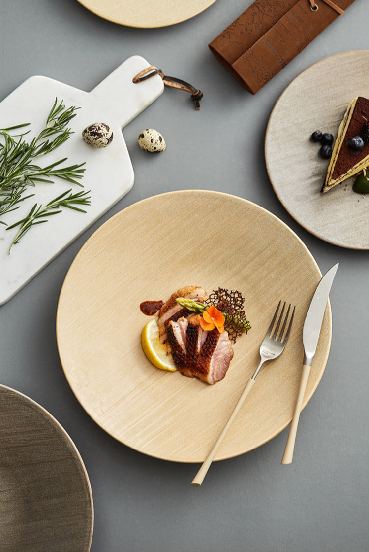 Dinner setting with a plate of food, fork, and knife on a gray surface.