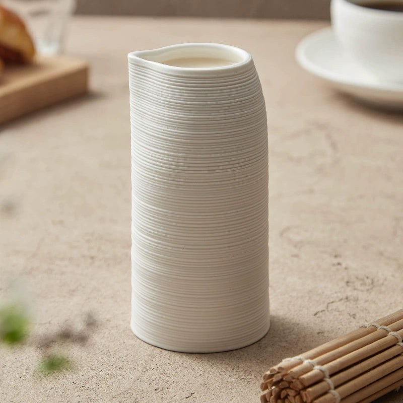 White textured vase on a light surface with a blurred background