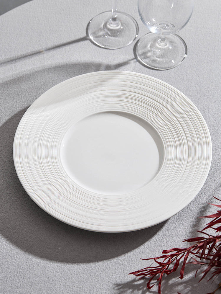 White ceramic plate on a gray surface with two clear glasses in the background.