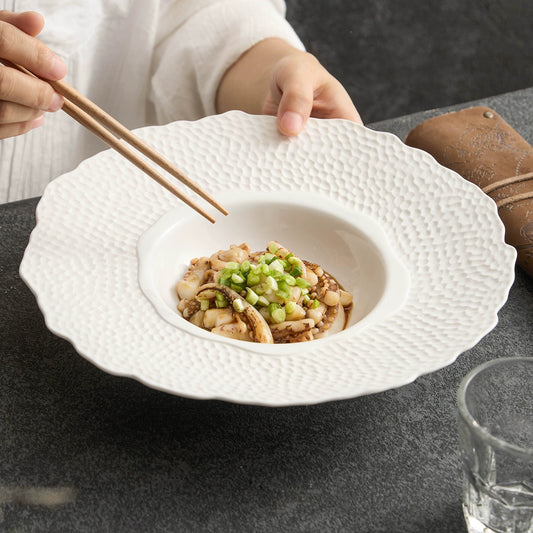 White ceramic plate with petal-shaped edge and hammered texture

