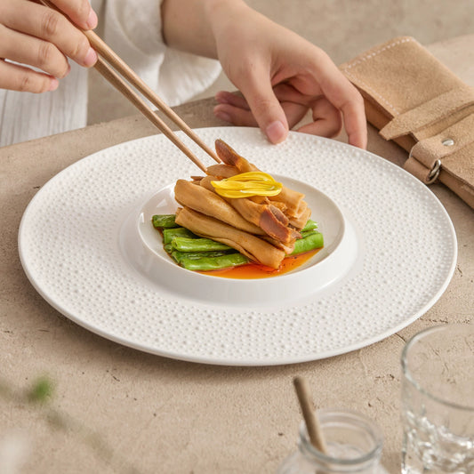 White porcelain dinner plate featuring subtle embossed rim and recessed center