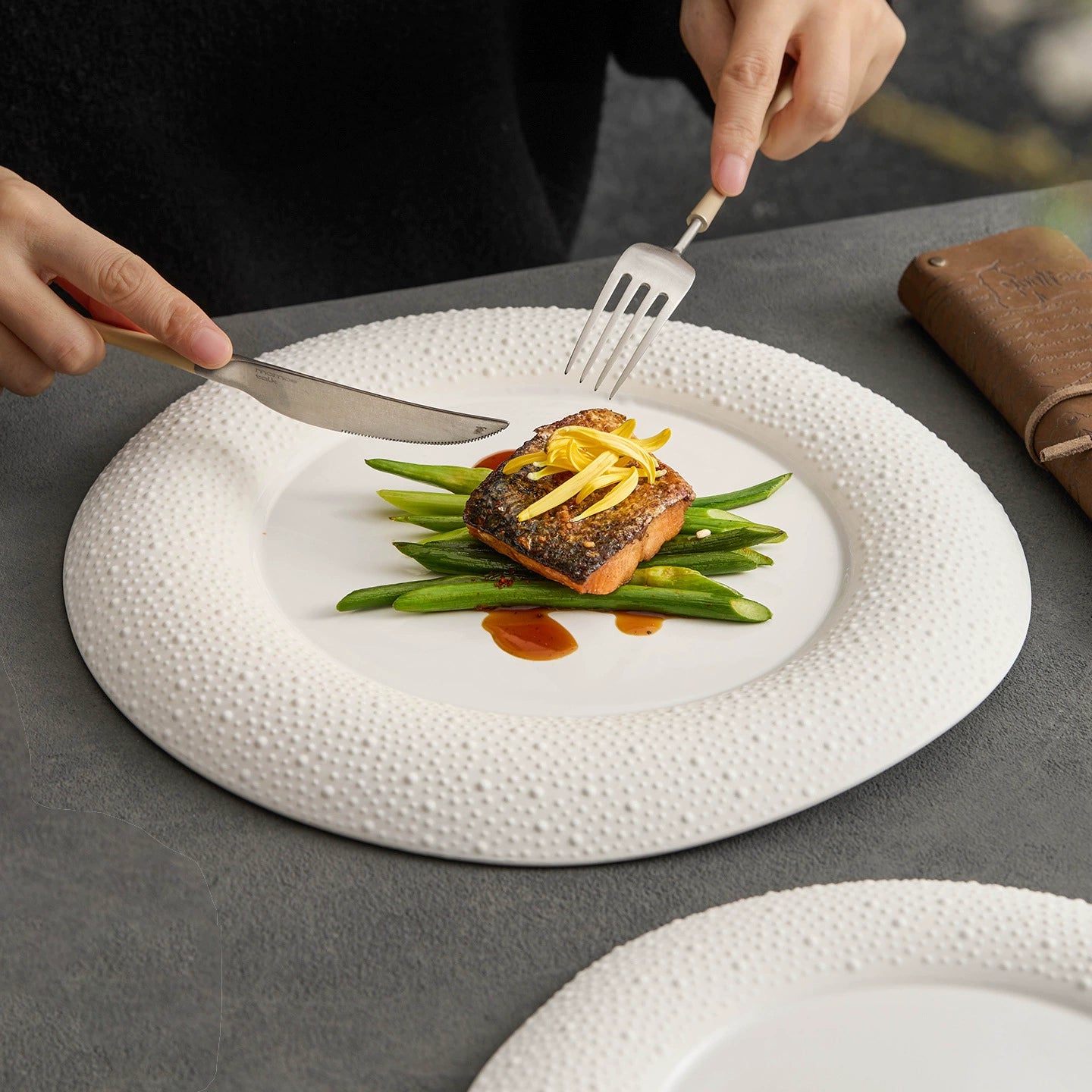 White porcelain plate with matte finish and dotted rim on dark stone background.