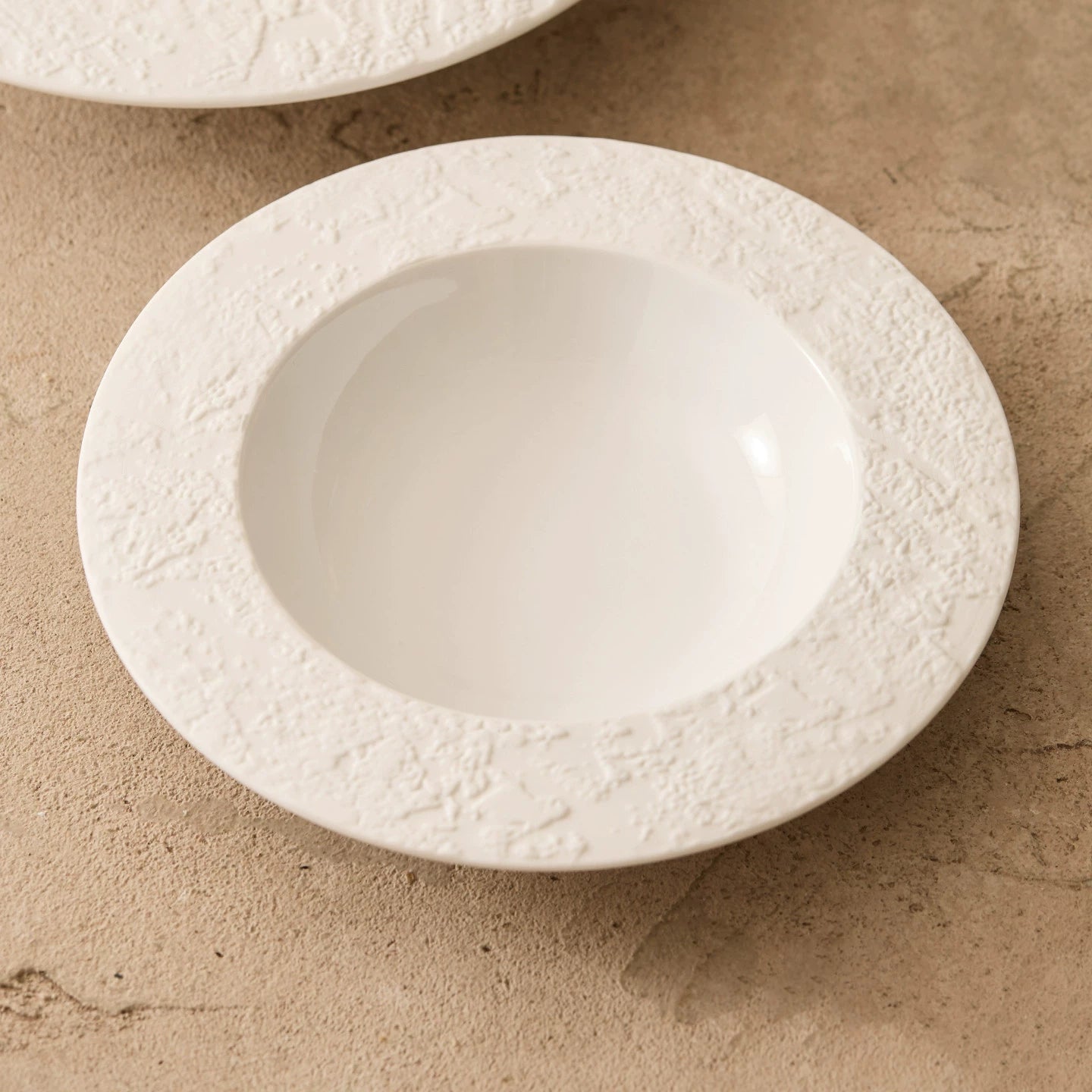 artisanal white ceramic pasta dish with organic carved rim