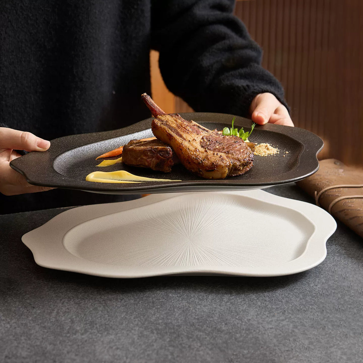 black matte irregular shaped dinner plate with lamb chops and sauce