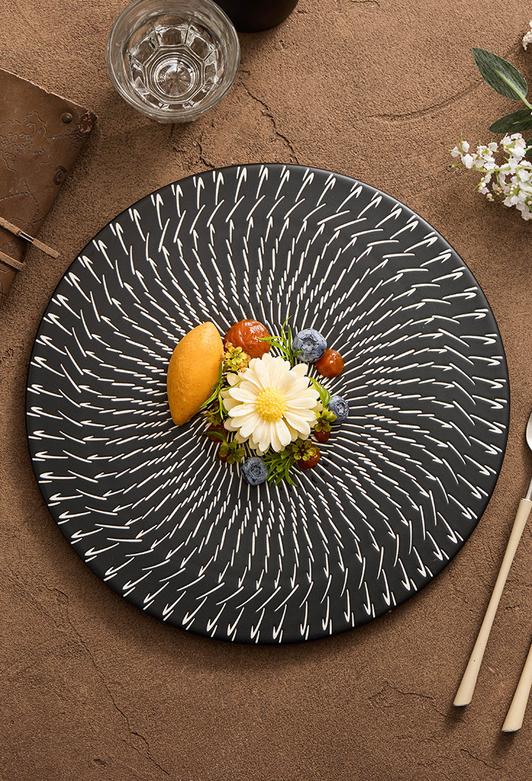 Decorative black plate with a floral arrangement on a brown surface