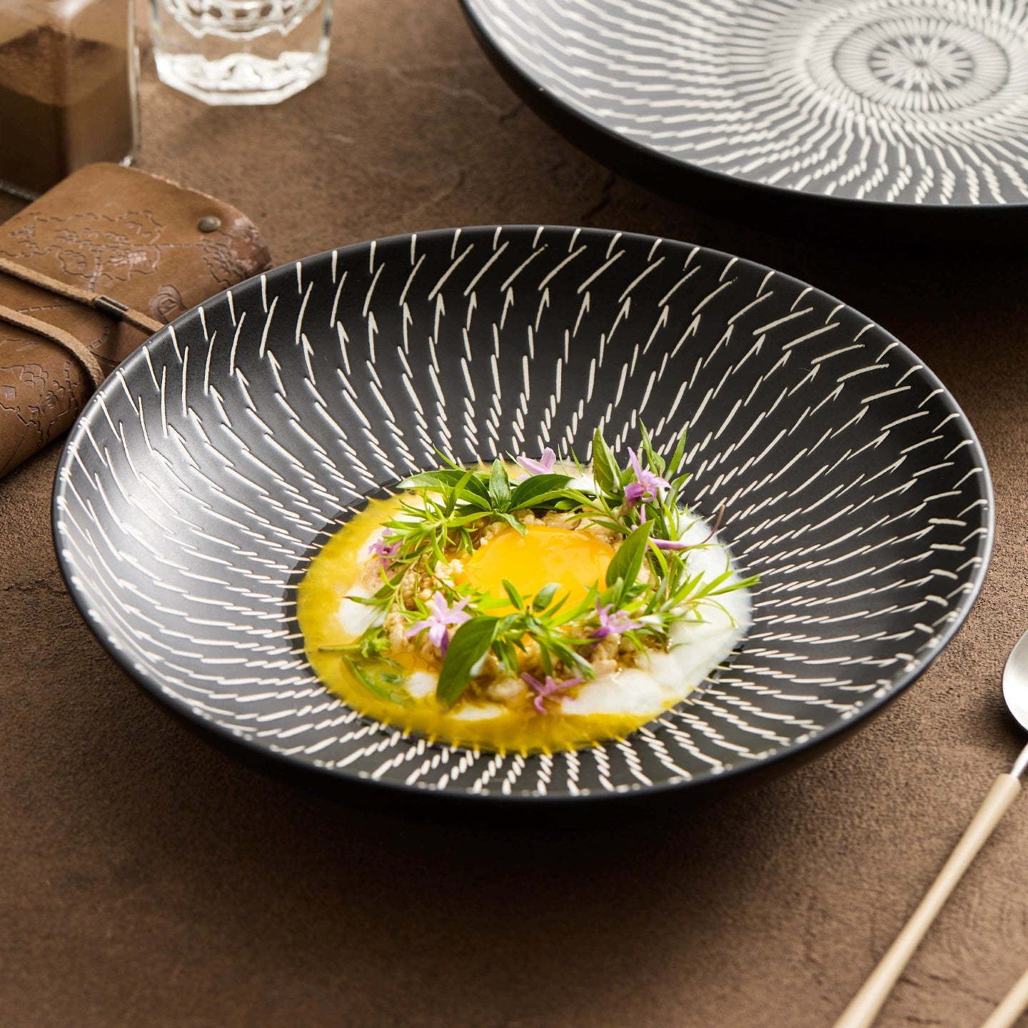 Decorative black plate with a dish of food on a brown table