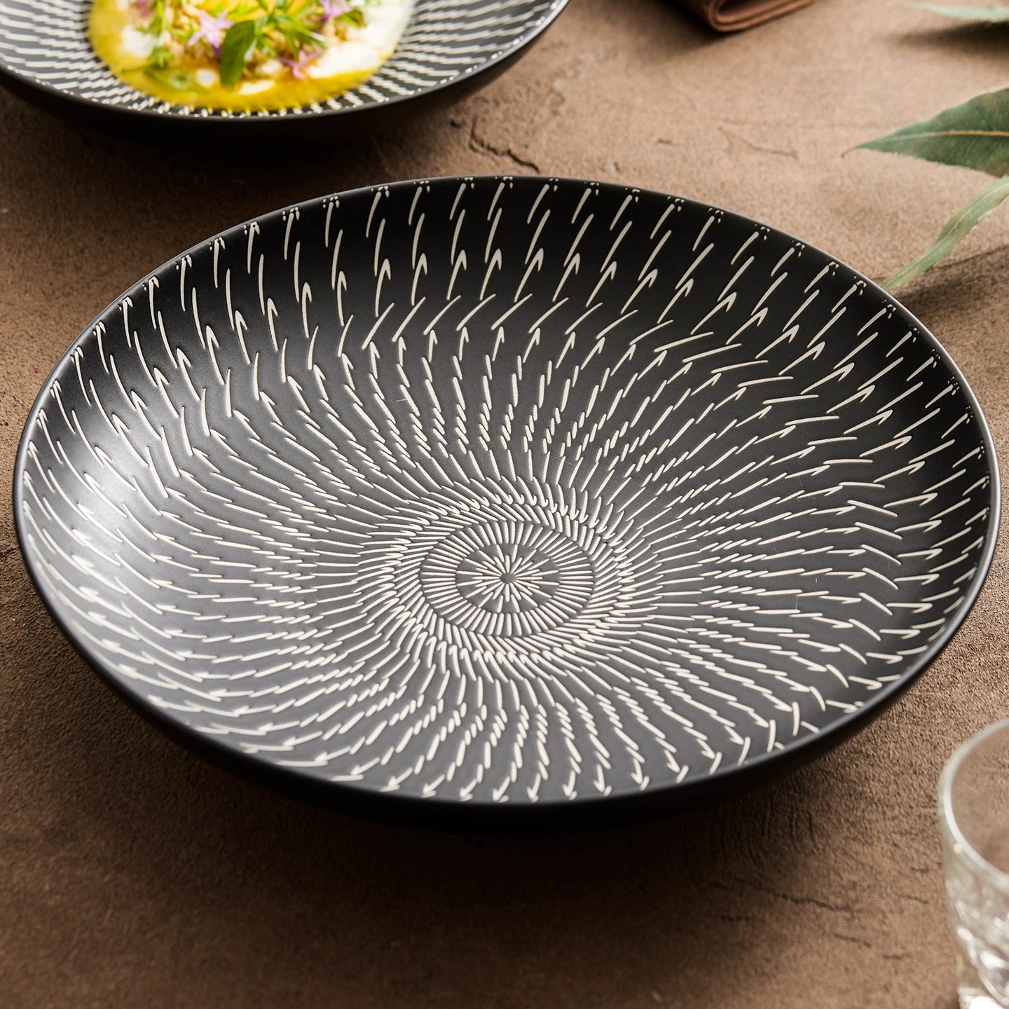 Black ceramic plate with white concentric patterns on a brown surface