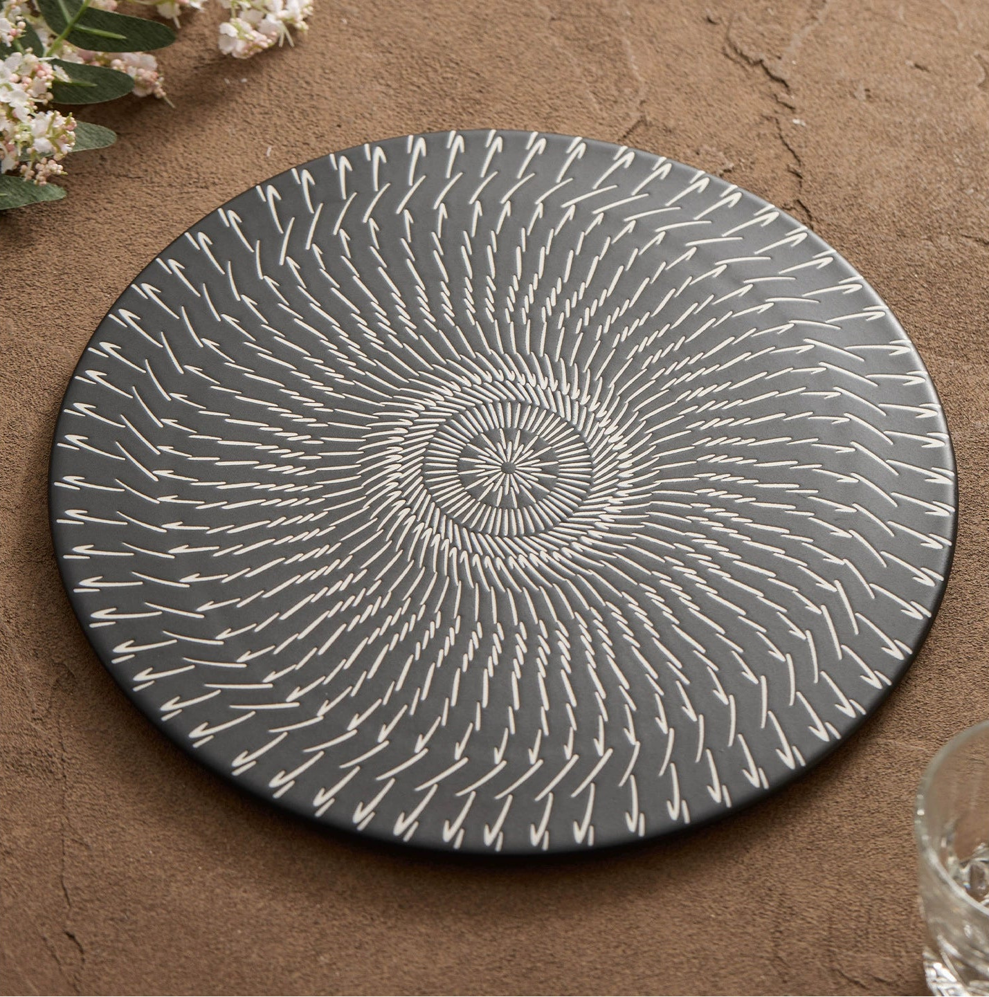 Round gray plate with white concentric circle pattern on a brown surface